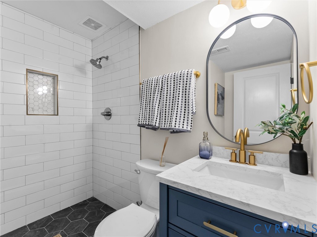 Subway tile shower surround with hexagon tile floor, a shower niche, and a rain shower head