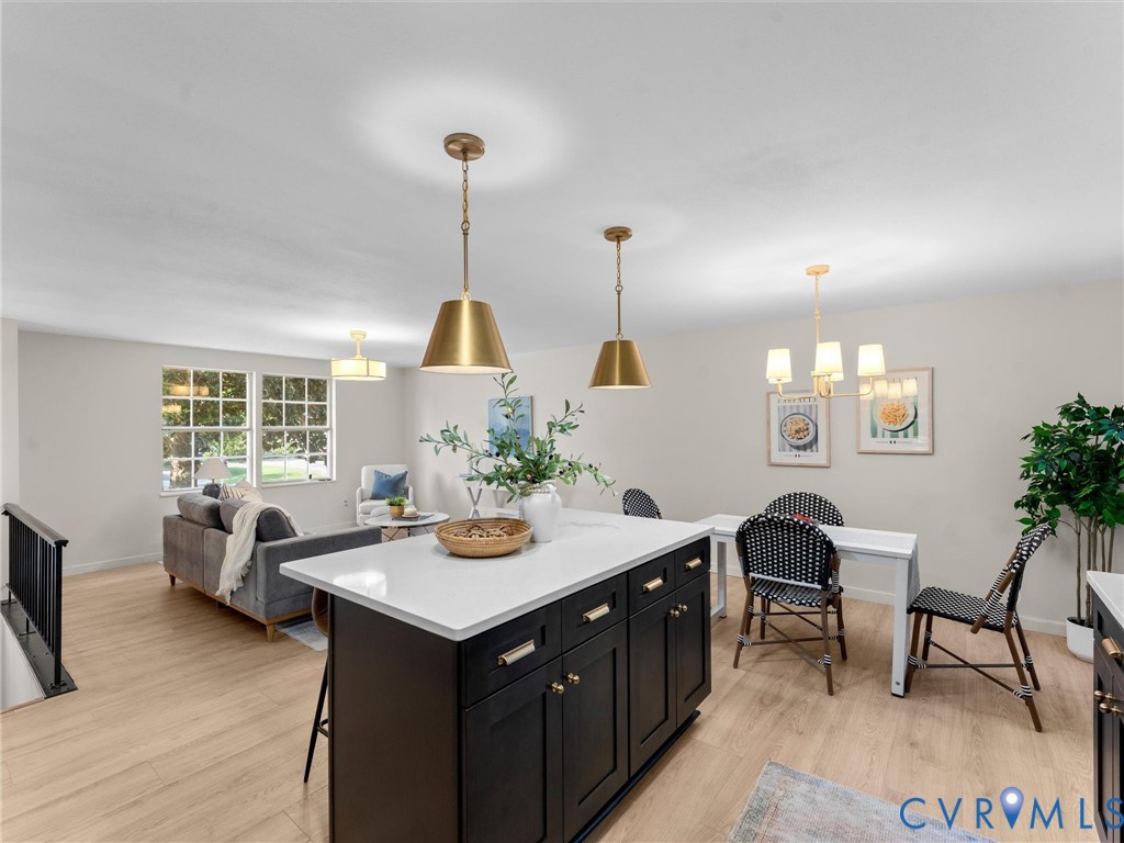 Open-concept living area featuring light wood-finish flooring, white walls, and multiple windows