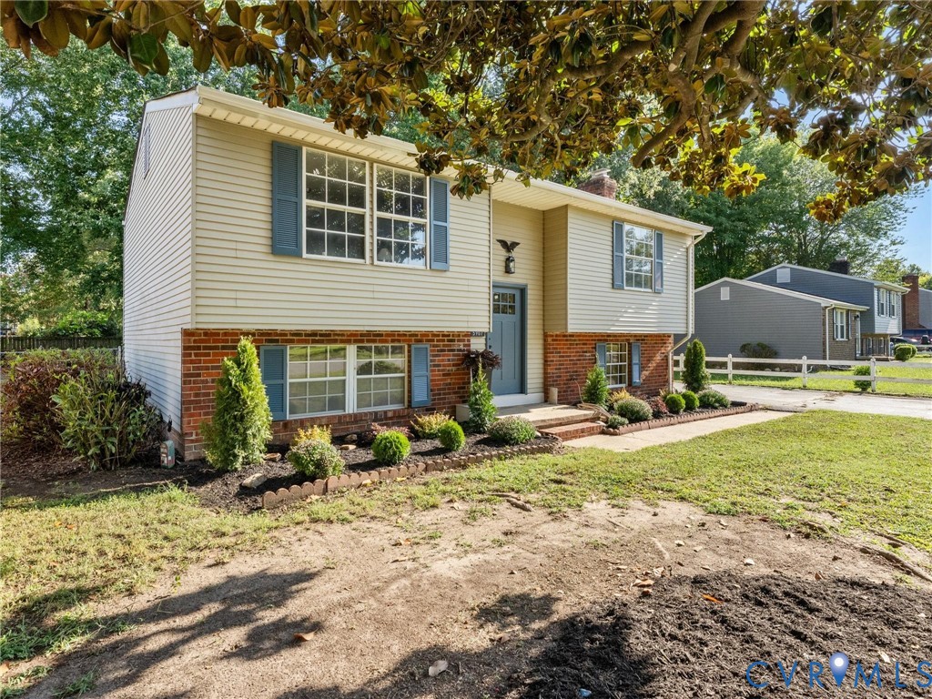 Two-story exterior with siding and brick accents, blue shutters, a blue front door, and a landscaped garden bed