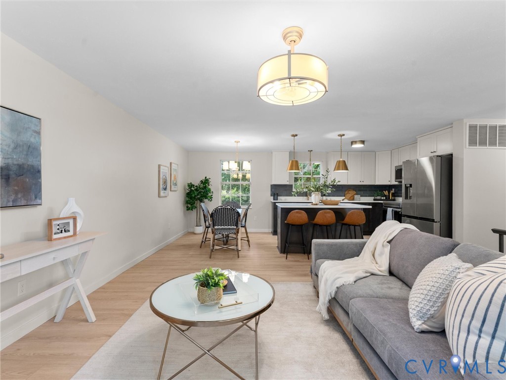 Open-concept living space featuring wood-finish flooring, recessed lighting, and a modern kitchen with a large island and stainless steel appliances