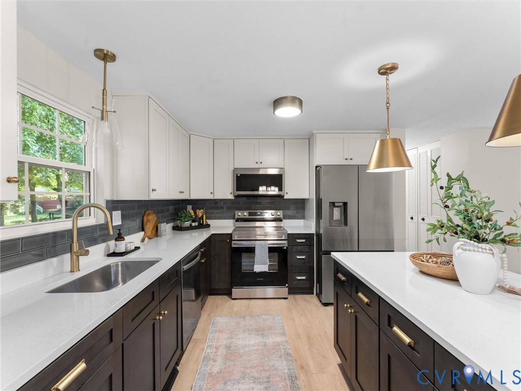 Modern kitchen featuring two-tone cabinetry, stainless steel appliances, white countertops, and a subway tile backsplash