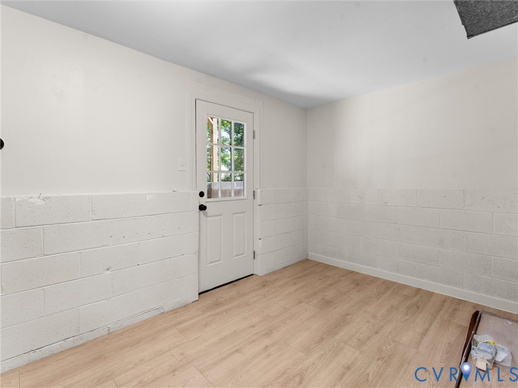 Wood-finish flooring with white painted walls and a block foundation wall