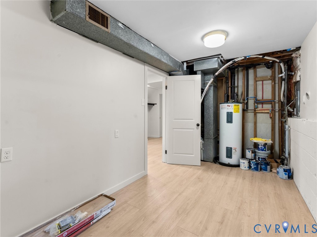 Light-toned wood-finish flooring, white painted walls, and a ceiling-mounted light fixture