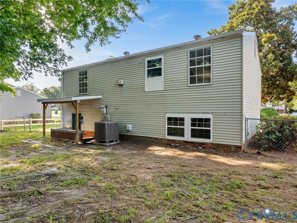 Rear exterior with horizontal siding, covered porch with wood supports, and chain-link fencing