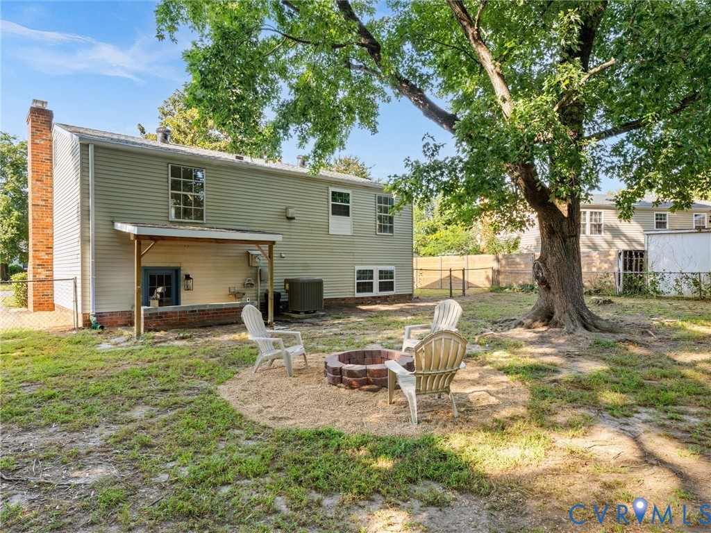 Rear exterior with a brick chimney, covered patio, multiple windows, and a mature tree