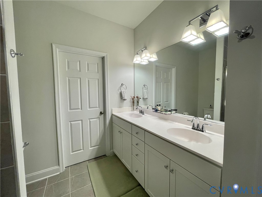 Double vanity with white cabinetry, integrated sinks, white countertops, and chrome fixtures