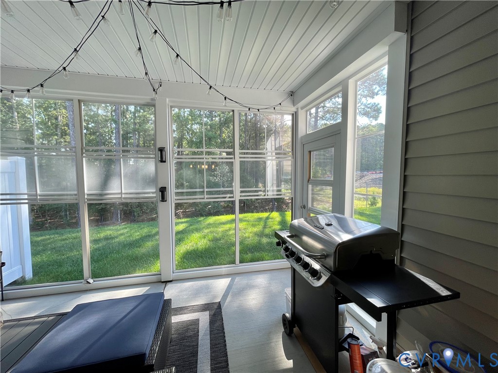 Screened-in porch featuring a beadboard ceiling, exterior siding, and a door providing access to the yard