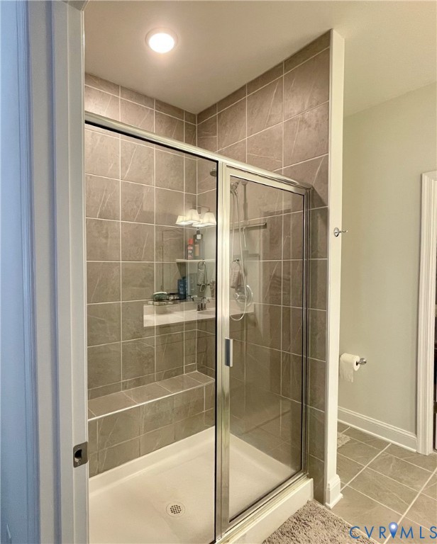 Shower enclosure featuring clear glass sliding doors, full-height tile surround, an integrated bench, and a recessed niche