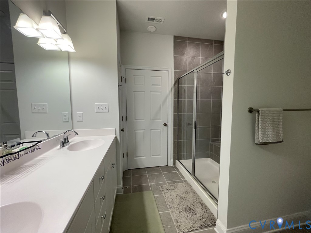 Dual sink vanity with white countertop, chrome fixtures, and mounted mirror
