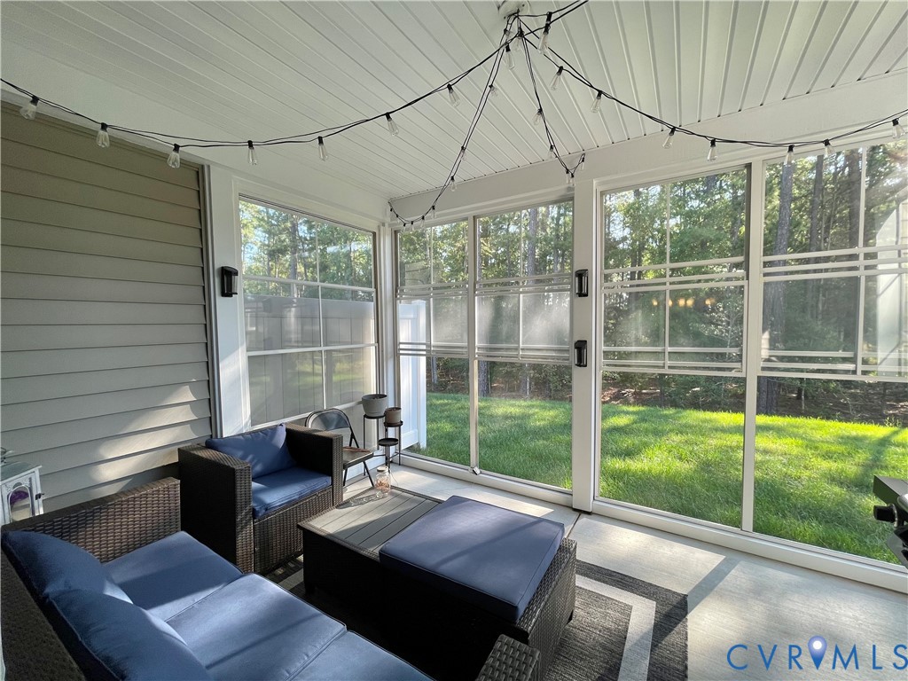 Screened-in porch featuring a vaulted white paneled ceiling, durable concrete flooring, and multiple window panels
