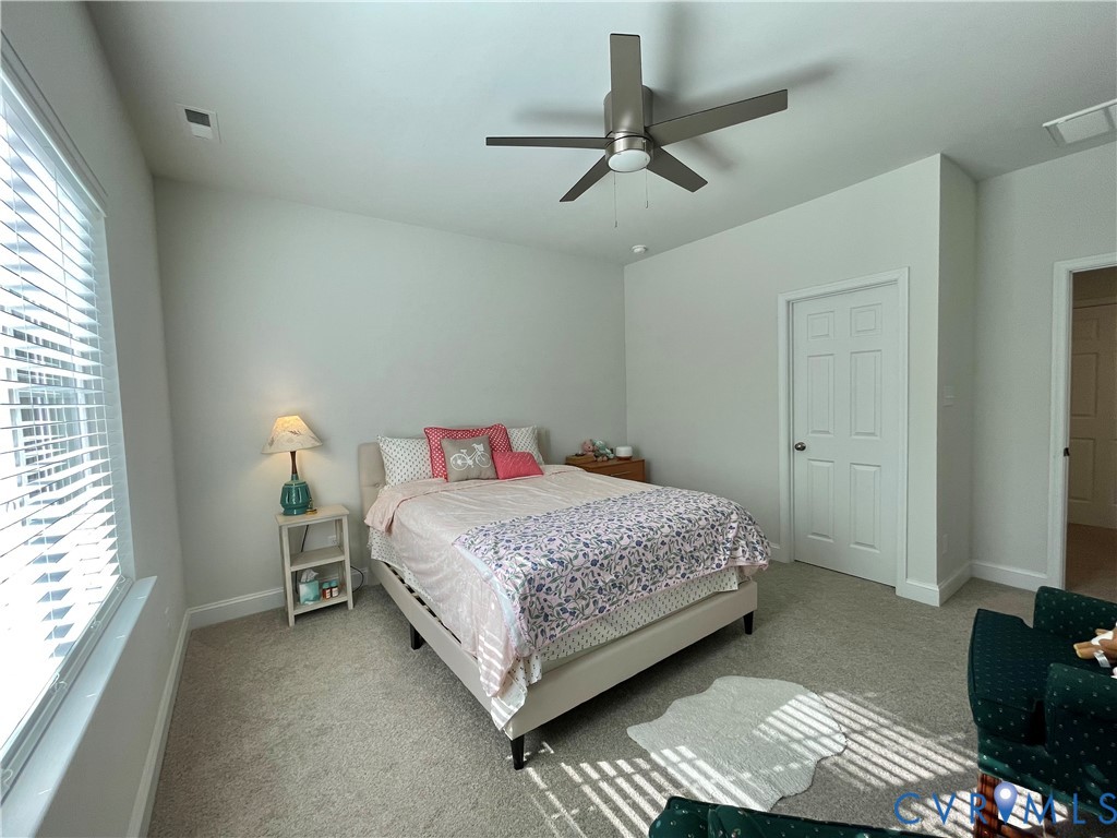 Wall-to-wall carpeting, ceiling fan, white paneled doors, and window with blinds