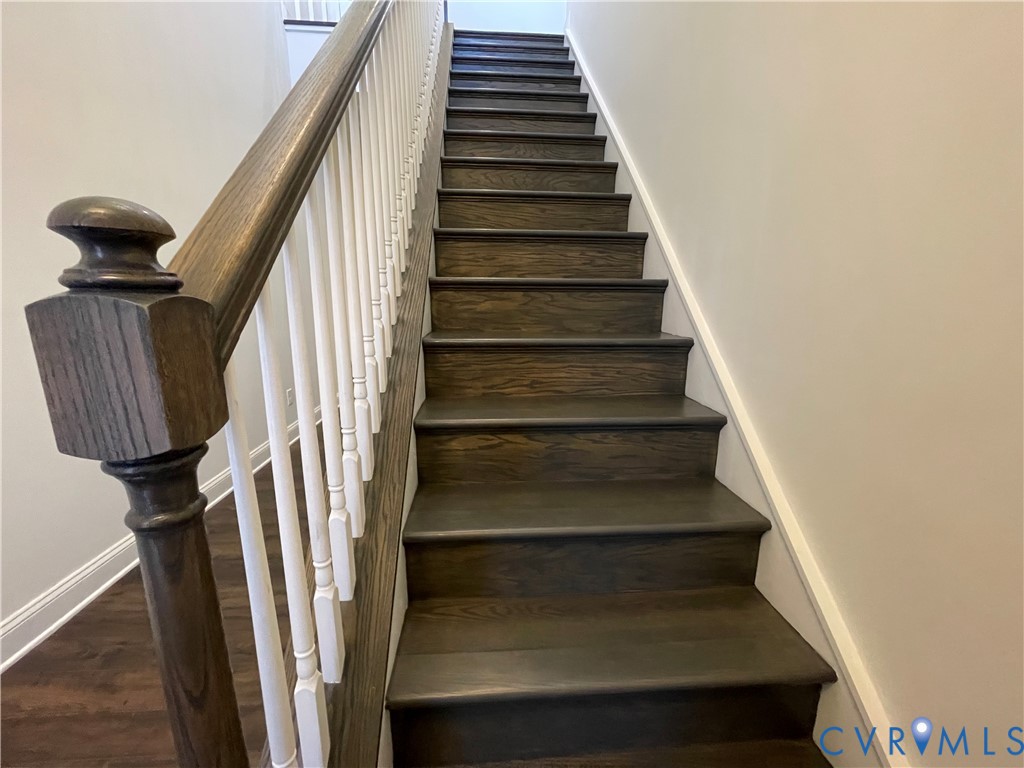 Staircase featuring wood treads, painted risers, wood newel post, and white balusters