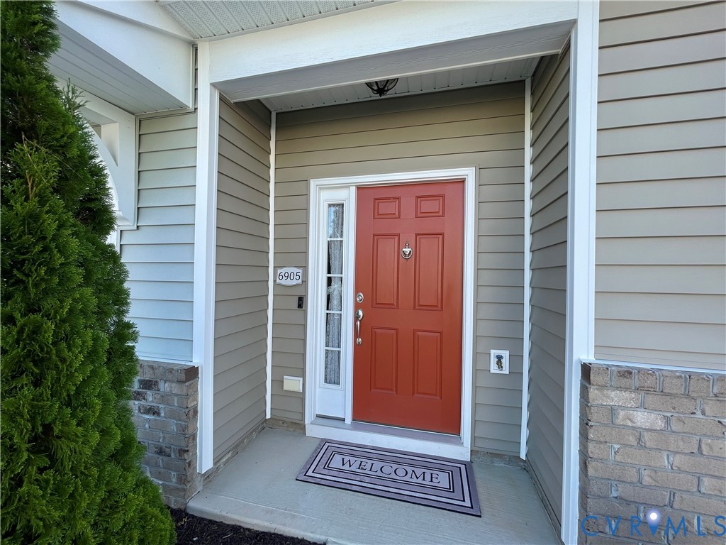 Entryway featuring a panel door with sidelight, overhead lighting, and concrete porch