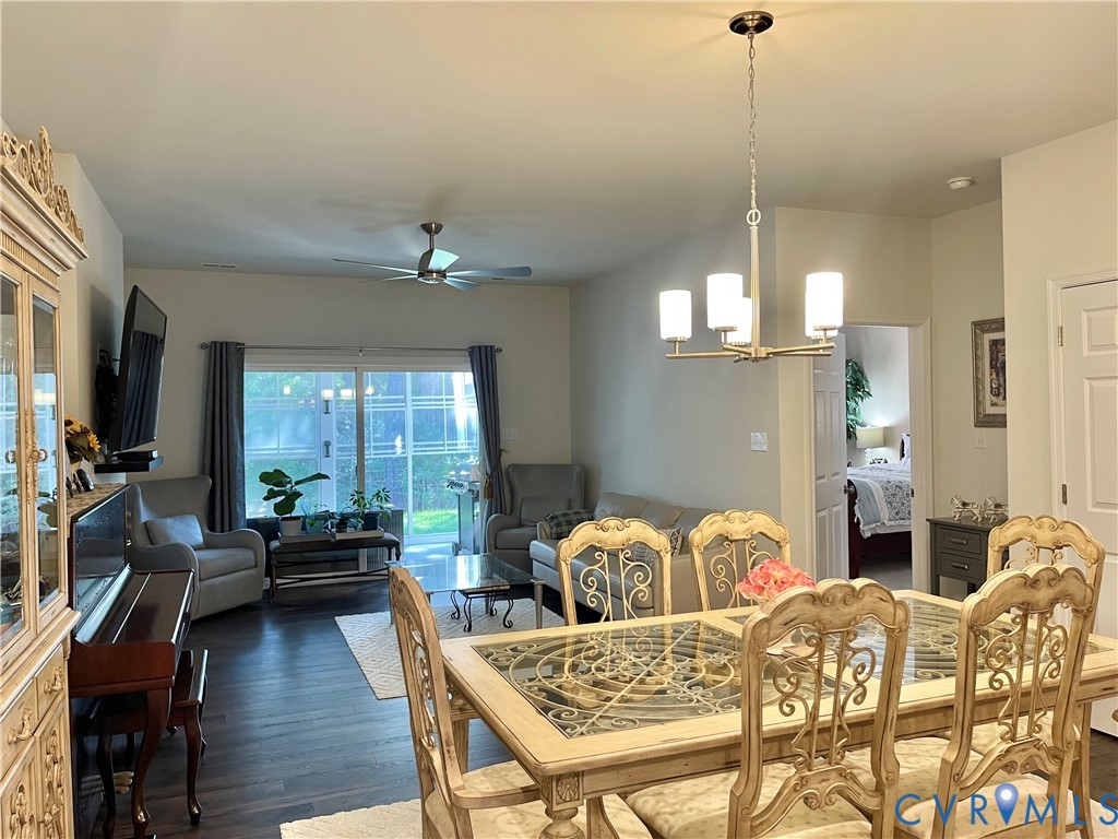 Open-concept living and dining areas featuring dark wood-finish flooring, a contemporary chandelier, and a ceiling fan