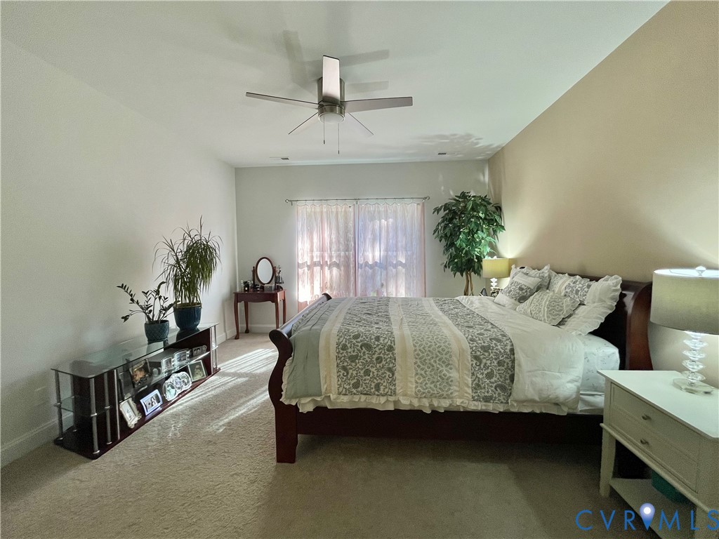 Wall-to-wall carpeting, ceiling fan with light fixture, and windows with vertical blinds