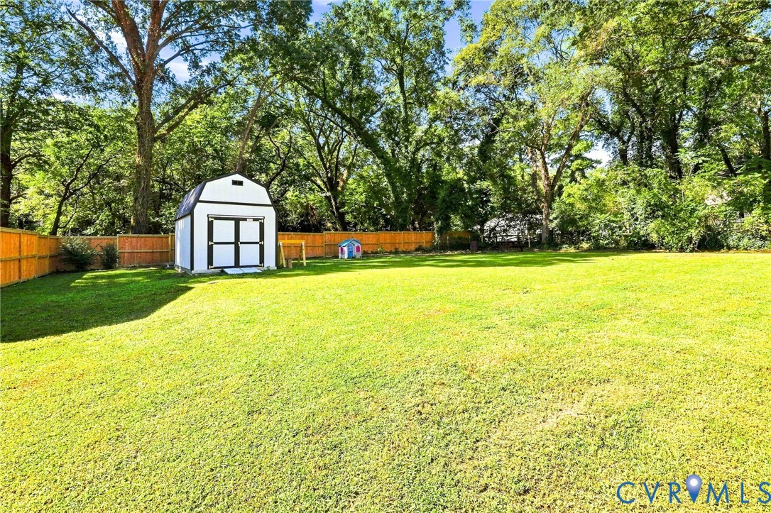 Large back yard with a new storage shed, wood privacy fencing, and mature perimeter trees