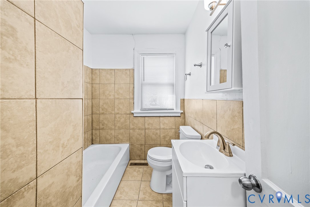 Bathroom with a white vanity featuring an integrated sink, brushed brass-finish faucet, and coordinating wall-mounted light fixture