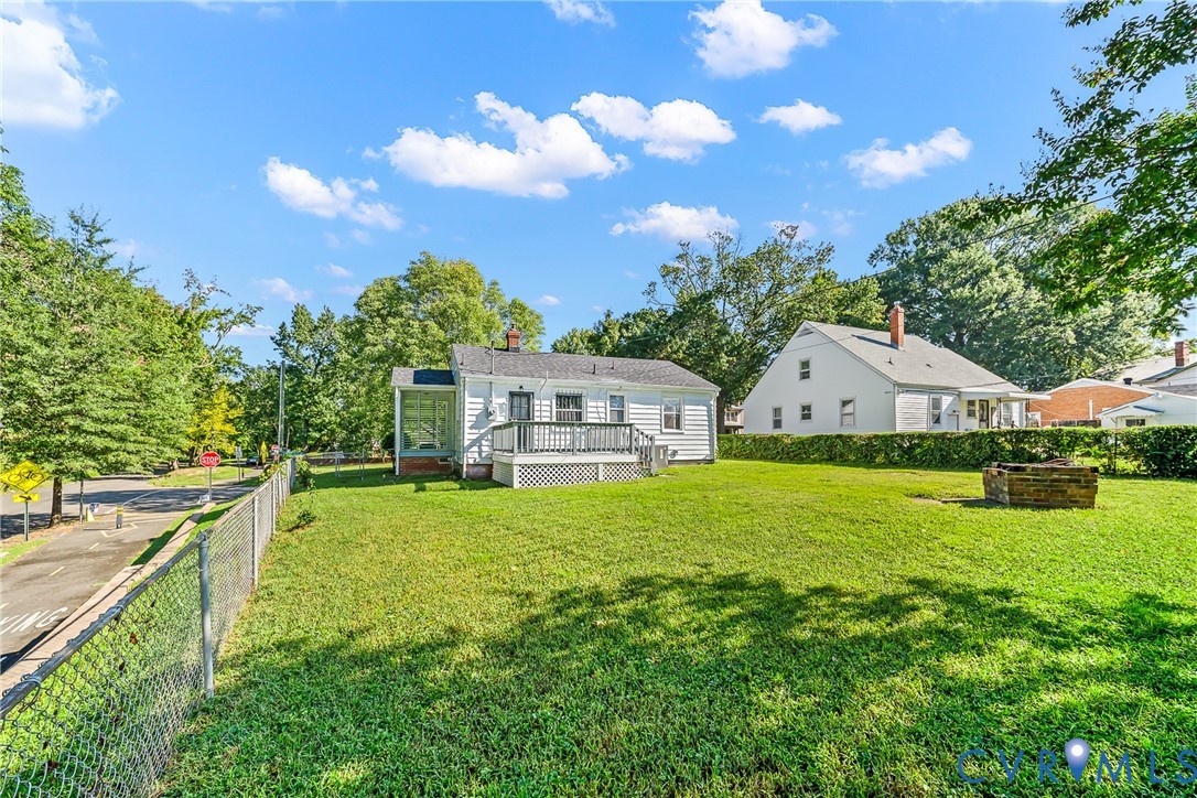 Expansive fenced yard featuring a wood deck, screened porch, and a built-in fire pit