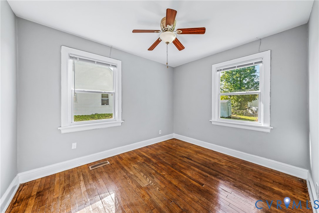 Hardwood flooring, painted walls, white trim, two windows, and a ceiling fan