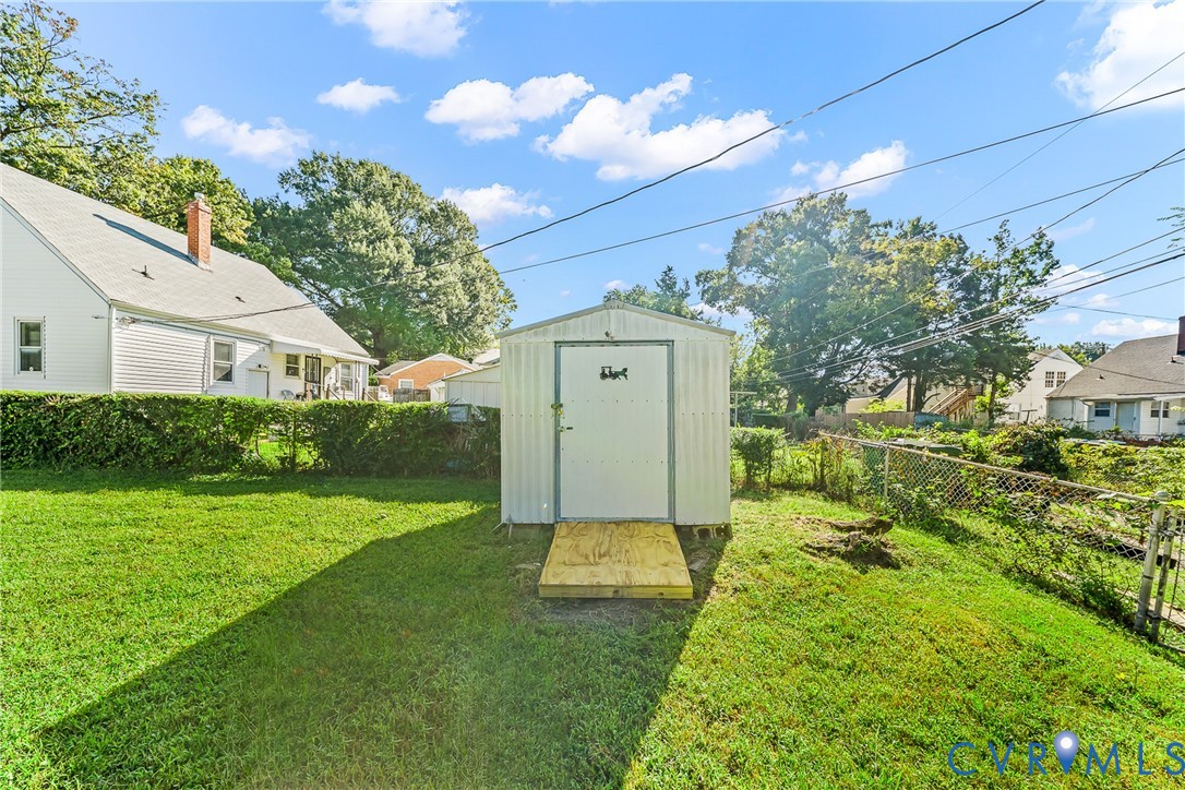 Expansive yard featuring a metal storage shed, wood ramp entry, and chain-link fencing