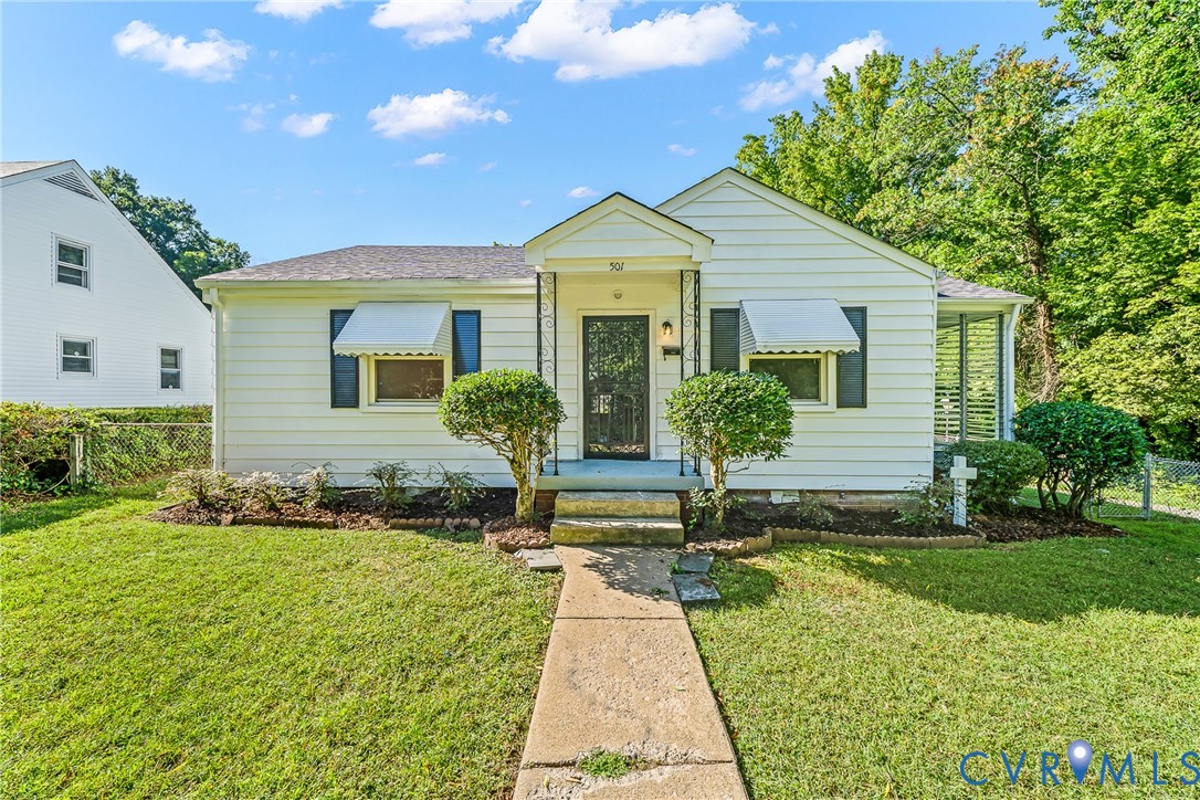 White siding exterior with a pitched roof, front entry porch, window awnings, and a concrete walk