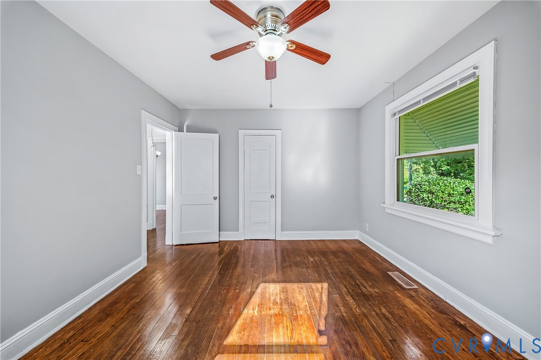 Hardwood flooring, ceiling fan, white trim, and a window with natural light