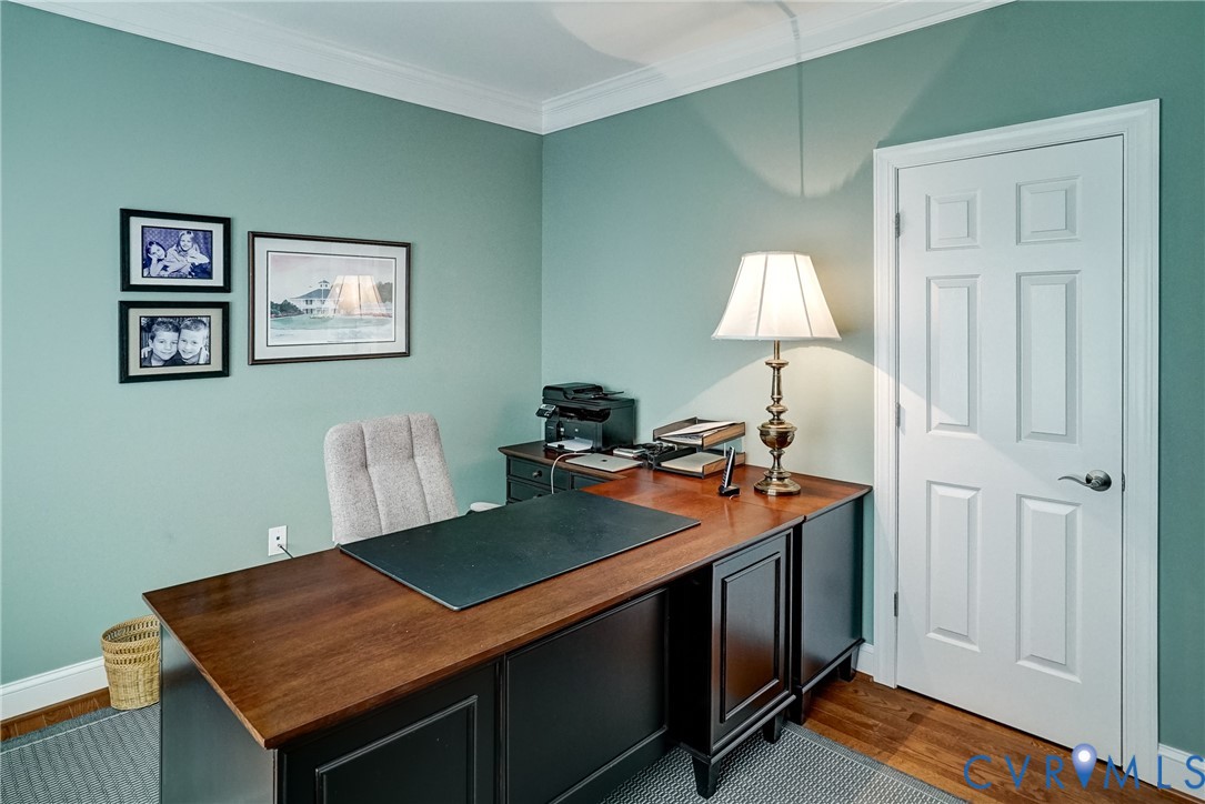 Wood-finish flooring, crown molding, and a paneled interior door
