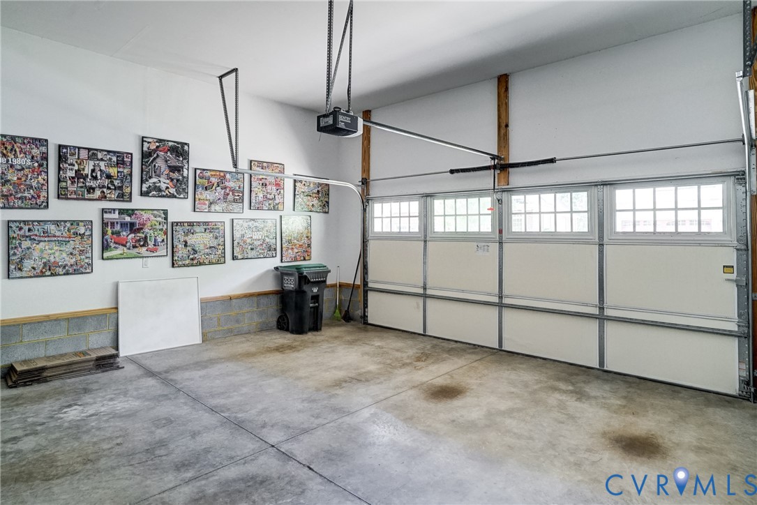 Garage space featuring a concrete floor, white walls, and an automatic garage door opener