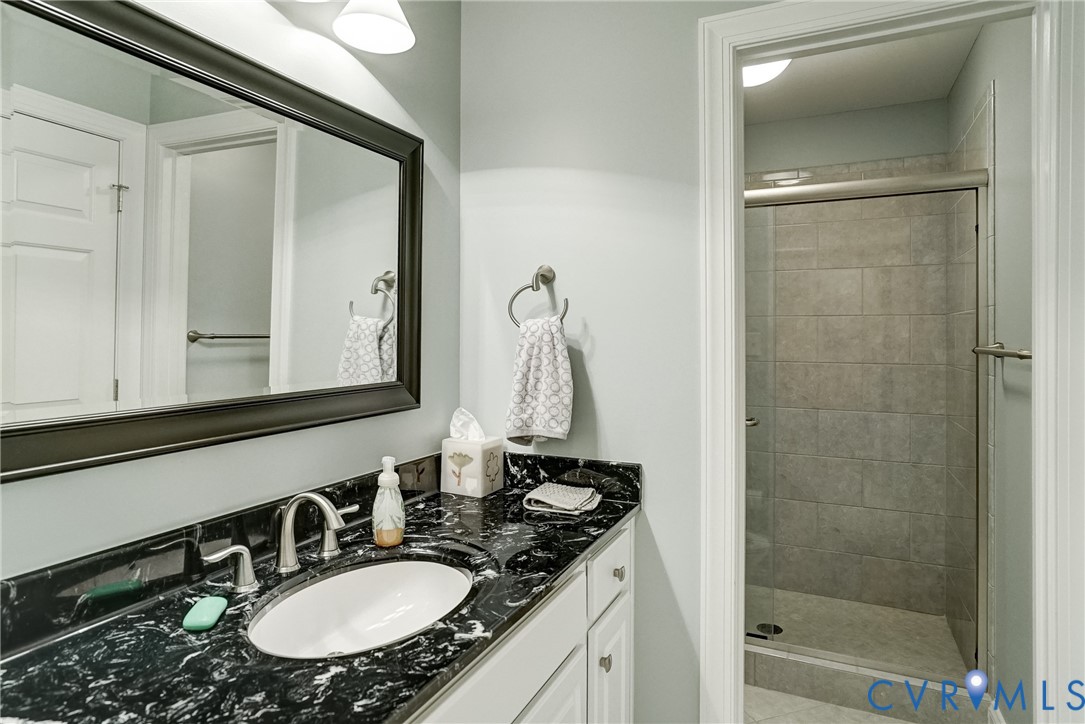 Vanity with a black stone countertop, undermount sink, and brushed nickel faucet