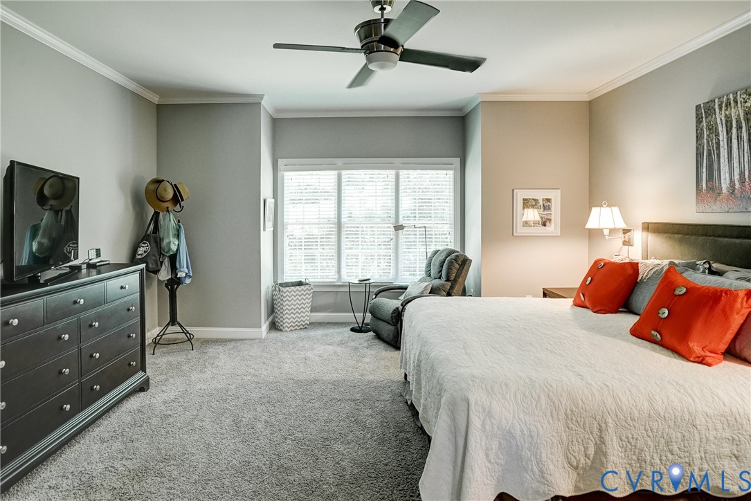 Spacious room featuring broadloom carpet, a large window with blinds, and crown molding