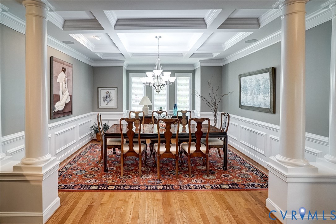 Coffer ceiling with recessed lighting, architectural columns, hardwood flooring, wainscoting, and a chandelier