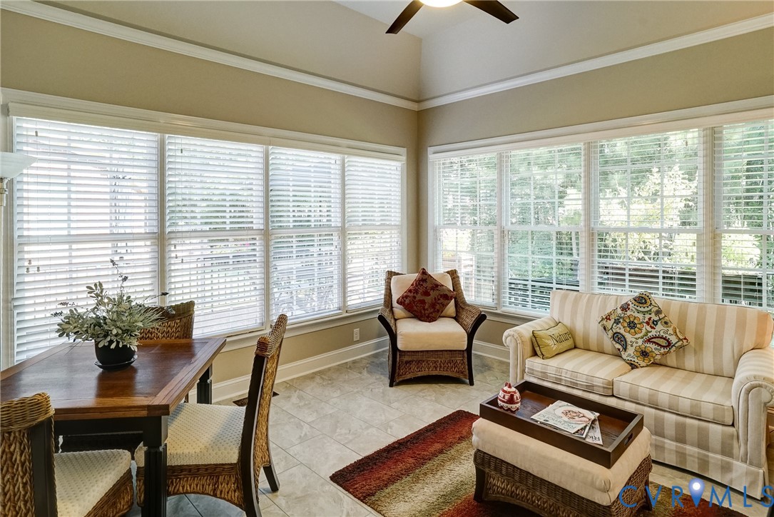 Vaulted ceiling, ceiling fan, extensive windows, crown molding, and tile flooring