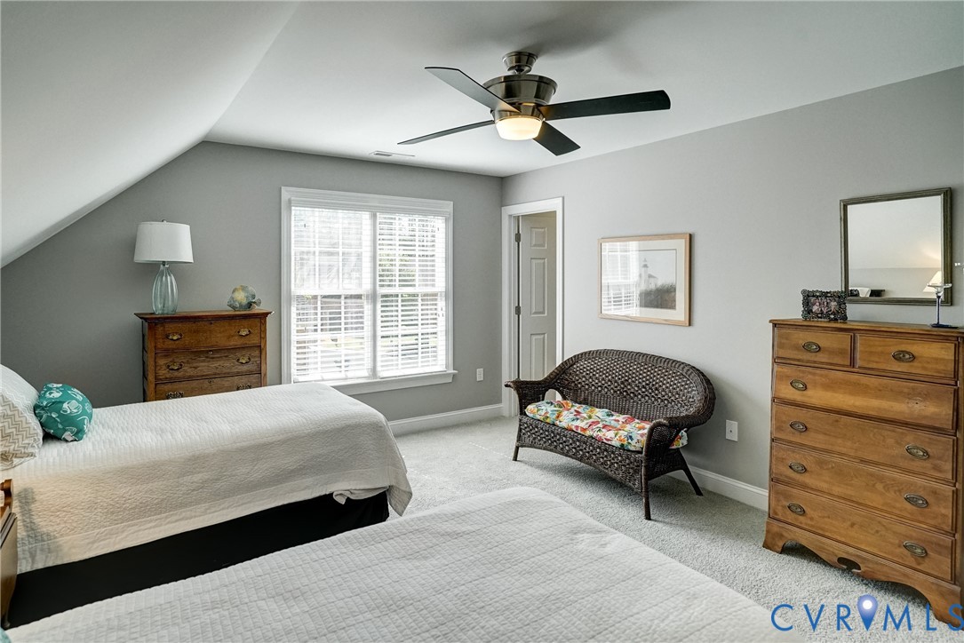 Sloped ceiling design, ceiling fan with integrated lighting, light gray wall paint, white window trim, and wall-to-wall carpeting