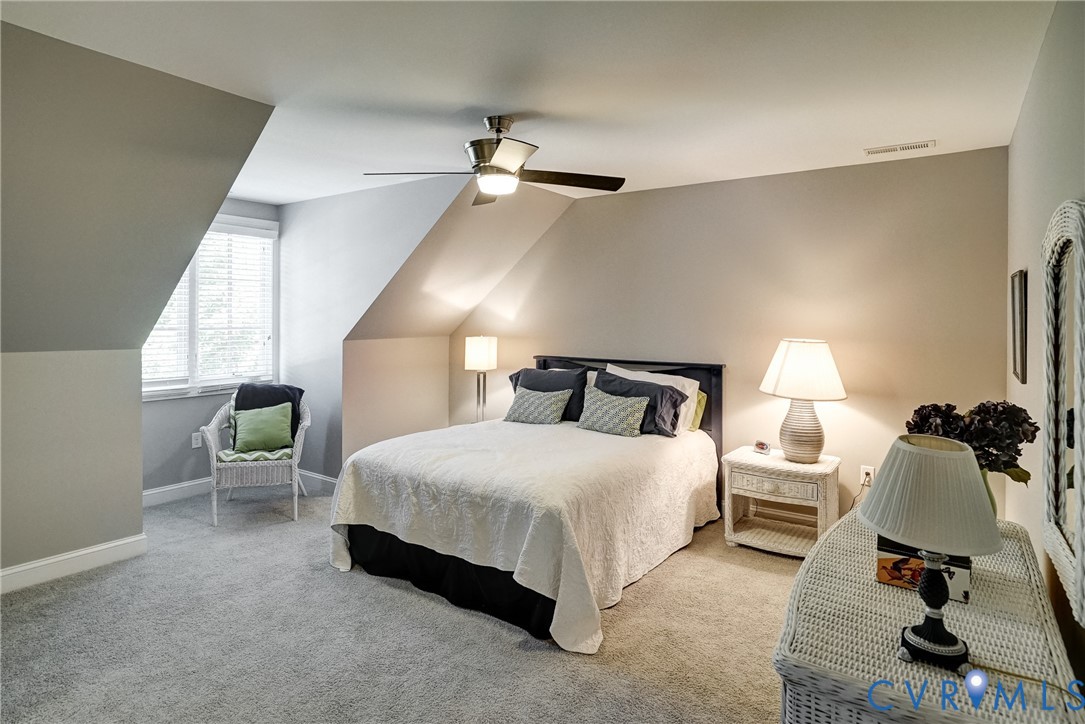 Room featuring carpet flooring, sloped ceiling design, a window with blinds, and a ceiling fan with integrated lighting