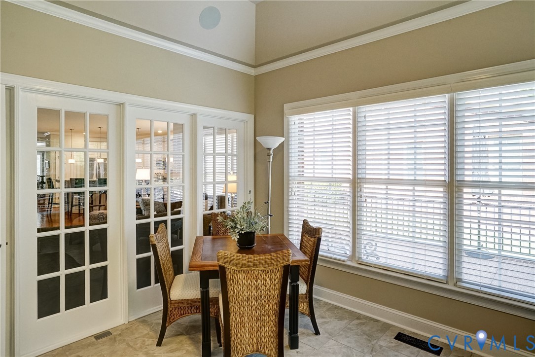 Vaulted ceiling with an integrated speaker, extensive crown molding, three large windows, and a tiled floor