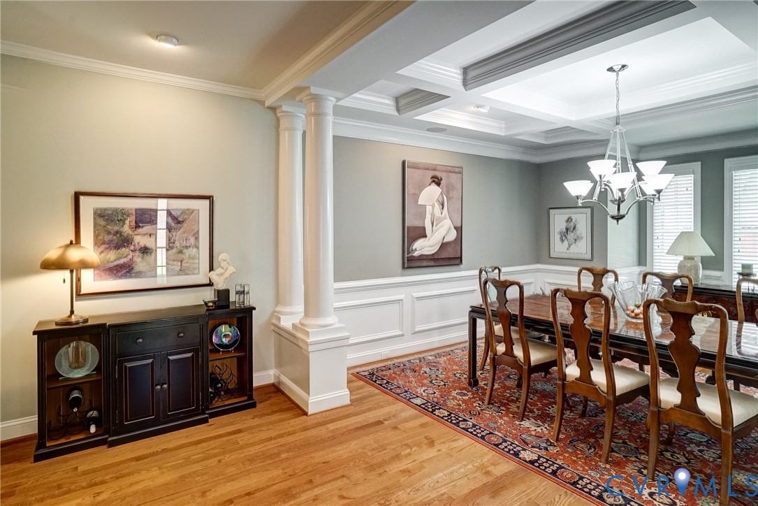 Hardwood flooring, decorative columns, wainscoting, recessed lighting, and a chandelier