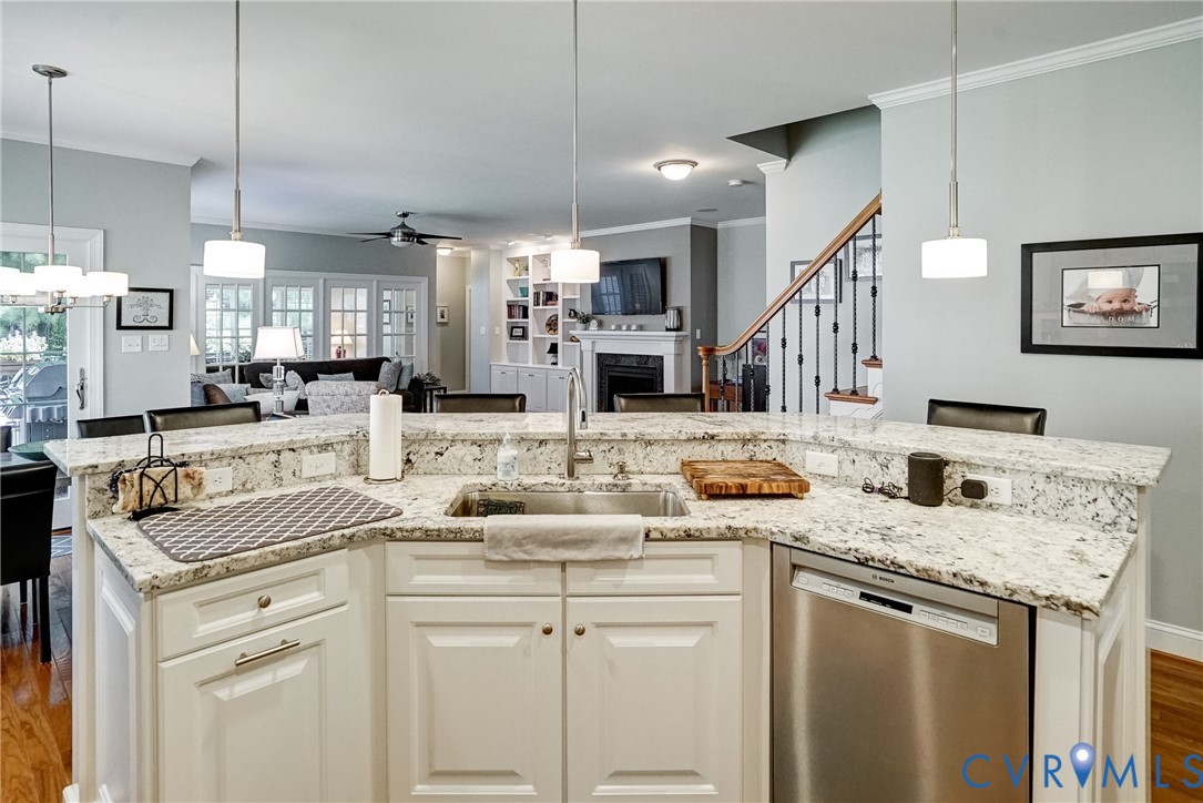 Kitchen island with granite countertops, stainless steel sink, and integrated dishwasher