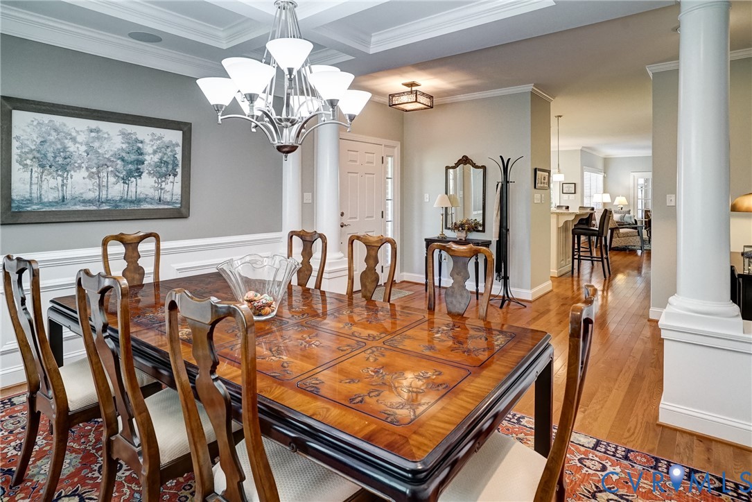 Formal dining area with coffered ceiling, chandelier lighting, and hardwood flooring
