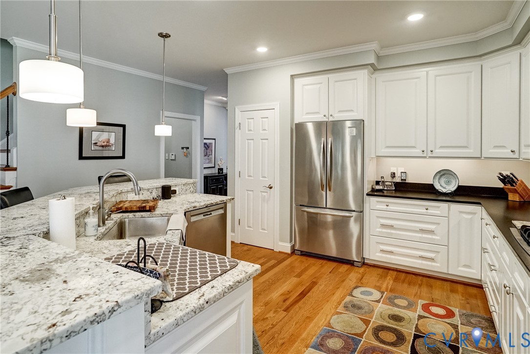 Kitchen featuring white cabinetry, stainless steel appliances, light-toned countertops, hardwood flooring, and recessed lighting