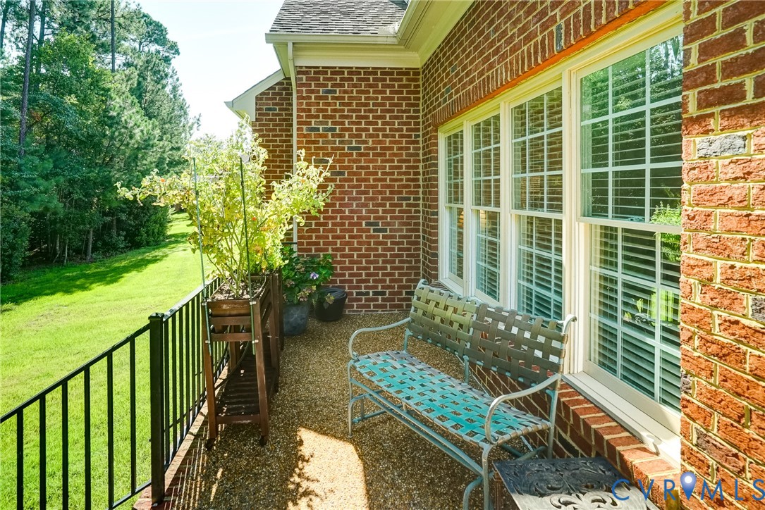 Brick exterior with multiple windows, a gravel-finished patio, and a black metal railing