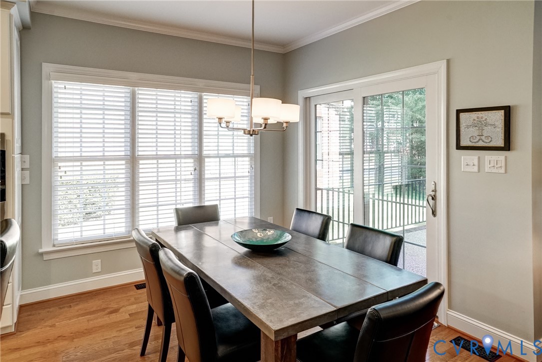Hardwood flooring, crown molding, white trim, sliding glass door, and a multi-light chandelier