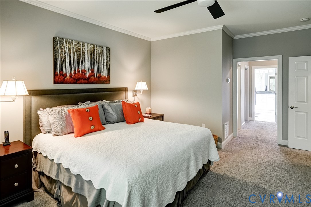 Carpeted room featuring a built-in upholstered headboard, white trim, and a ceiling fan