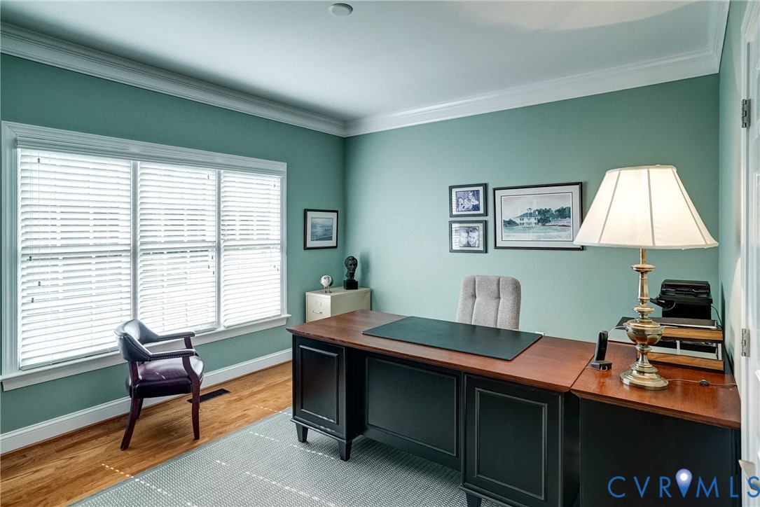 Hardwood flooring, crown molding, white window trim, and a white paneled door