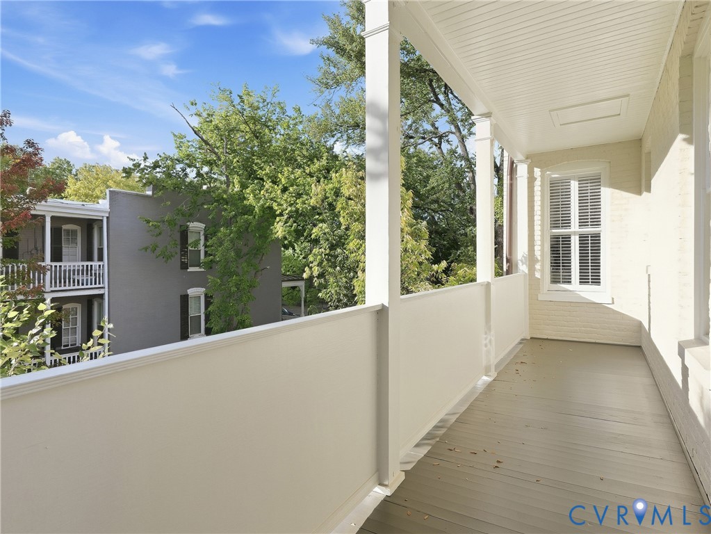 Covered porch with painted wood flooring, white painted support columns, and a white paneled ceiling