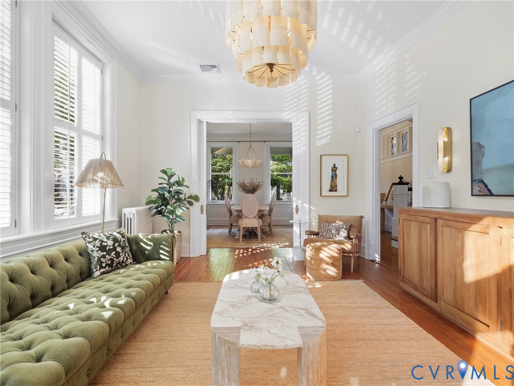 Hardwood flooring, crown molding, abundant natural light, recessed lighting, and a decorative ceiling fixture