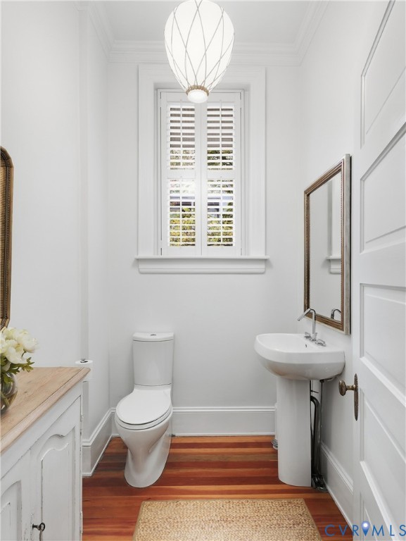 Pedestal sink, wood-finish flooring, plantation shutters, contemporary pendant light, and paneled door