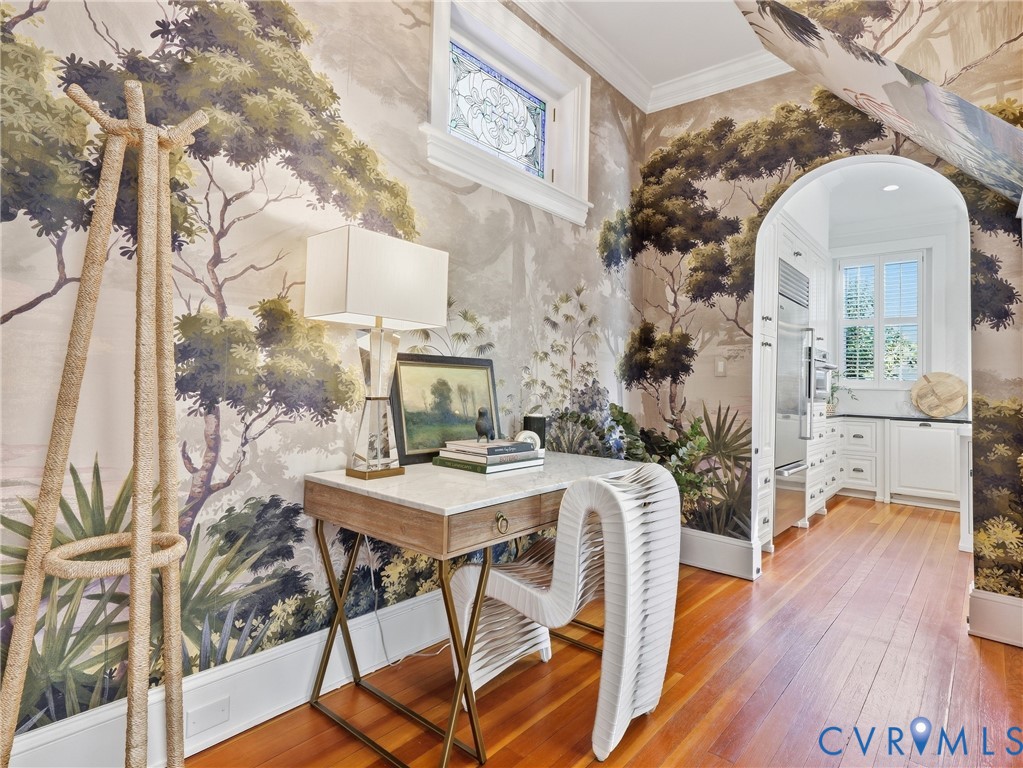 Hardwood flooring, arched doorway, custom wall covering, built-in cabinetry, and a stained-glass window
