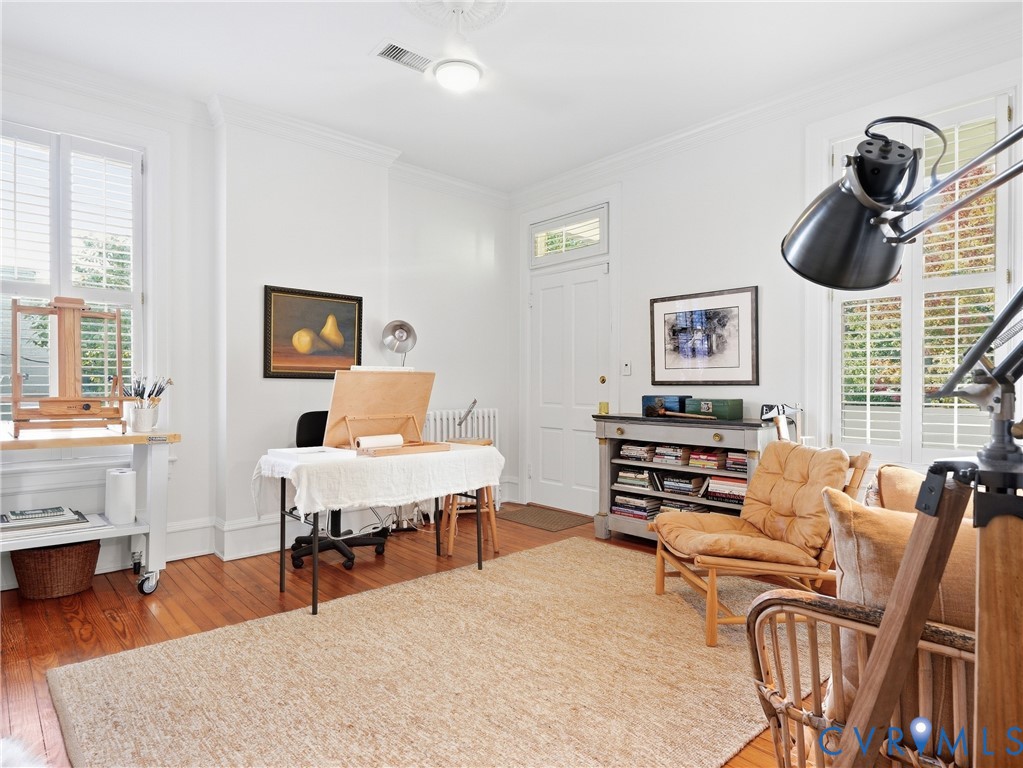 Hardwood flooring, crown molding, white painted walls, recessed lighting, and window shutters
