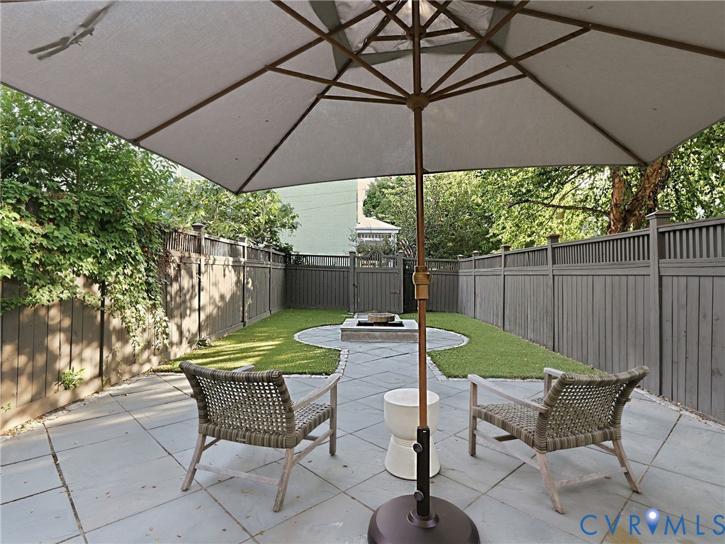Private backyard featuring a stone paver patio, a manicured lawn, and a perimeter fence