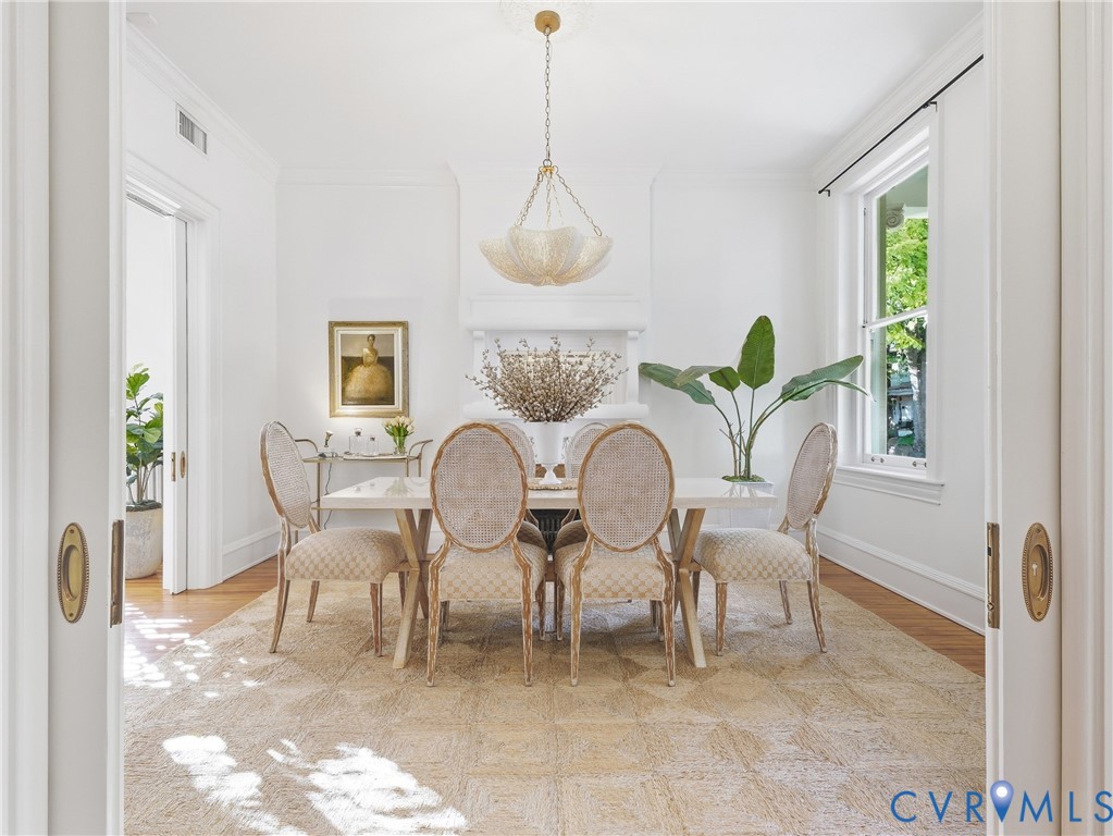 Recessed pocket doors with brass hardware, wood-finish flooring, and crown molding